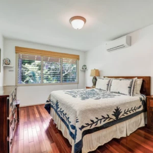 Relax in the comfortable bedroom at The Guest House with stunning river views and lush greenery at River Estate, Kauai. Bedroom view with river and lush greenery at The Guest House, River Estate, Kauai