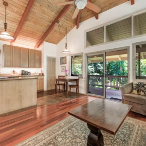 Step inside The Guest House at River Estate, Kauai, and enjoy the open layout connecting the kitchen and living area with elegant furnishings. View from the front door to the kitchen and living area of The Guest House at River Estate