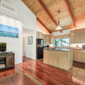 Relax in the elegant living room and kitchen of The Guest House at River Estate, Kauai, with top-quality furnishings and modern amenities. Living room and kitchen of The Guest House at River Estate with elegant furnishings and modern amenities