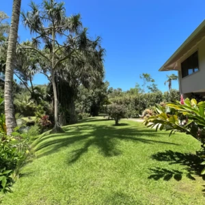 Discover the charm of The Guest House at River Estate, Kauai, with a welcoming entrance and lush front yard. Front view of The Guest House at River Estate with stairs leading to the entrance and lush front yard