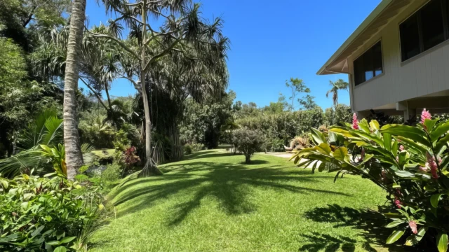 Discover the charm of The Guest House at River Estate, Kauai, with a welcoming entrance and lush front yard. Charming Entrance to The Guest House with Lush Greenery