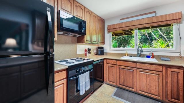 Discover the fully equipped kitchen at The River House, featuring modern appliances including a refrigerator and sink, perfect for your Kauai stay. Fully Equipped Kitchen with Modern Appliances