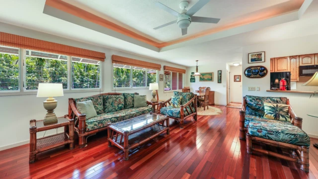 A bright and airy living room with tropical decor, featuring comfortable seating and a dining area. Perfect for a Kauai vacation rental. Stylish Living Room with Hutch and Dining Area View