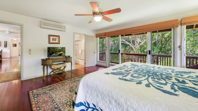 Enjoy the spacious master bedroom at The River House, River Estate, featuring a closet, hallway to the bathroom, and TV. Spacious Master Bedroom with Convenient Amenities