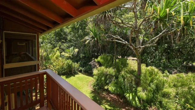 A serene view from a balcony overlooking lush greenery and a river, perfect for a peaceful retreat. Ideal for a Kauai vacation rental. Stunning River View from Master Bedroom Deck